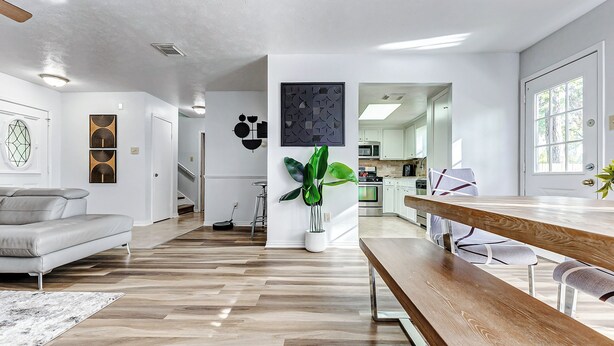 Una sala de estar moderna con un banco de madera, un sofá gris y una planta grande en maceta.