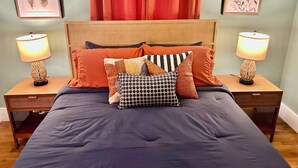 Une chambre à coucher avec un grand lit, deux tables de chevet, une tête de lit en bois et deux lampes fixées au mur.