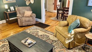 Un salon avec un canapé beige, une table basse en bois foncé et un tapis à motifs.