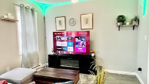 A living room with a flat-screen TV, a coffee table, a sofa, and a decorative plant.