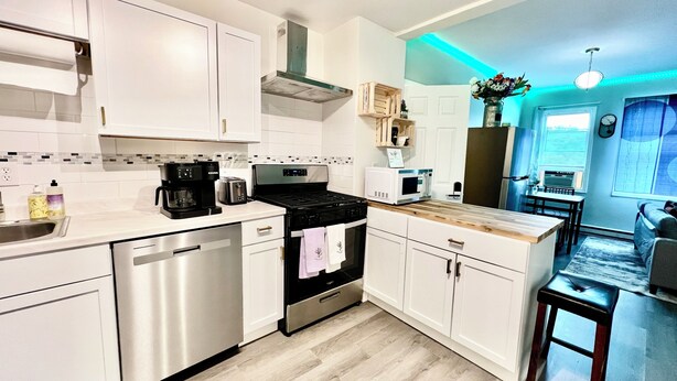 A modern kitchen with white cabinets, stainless steel appliances, and a wooden countertop.