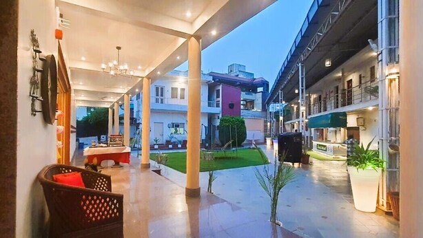 Un pasillo de hotel con una zona de estar techada, un pequeño jardín y vistas de los edificios circundantes.