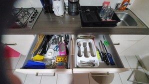 Een keuken met een fornuis, koffiezetapparaat en diverse keukengerei in lades.