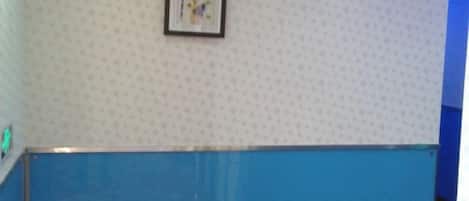 A room with a patterned wall, a framed picture, and a blue partition.