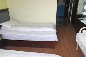 A room with two beds, a wooden floor, and a door leading to another room. - Shanghai Golden Hotel (Shanghai)