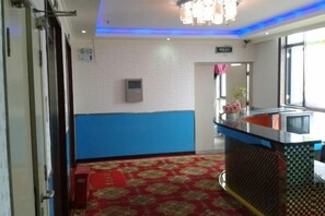 A hotel lobby with a reception desk, a red carpeted area, and a blue and white wall. - Shanghai Golden Hotel (Shanghai)