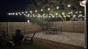 An outdoor patio with a wooden fence, string lights, and outdoor furniture. - Rockne Quad<>Updated 3BR 2BA Home 1 Mi to ND (South Bend)