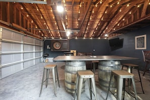A bar area with stools, a bar counter, and a dartboard.