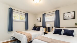 A hotel room with two beds, a nightstand, a lamp, a framed picture, and a window with curtains. - Rockne Quad<>Updated 3BR 2BA Home 1 Mi to ND (South Bend)