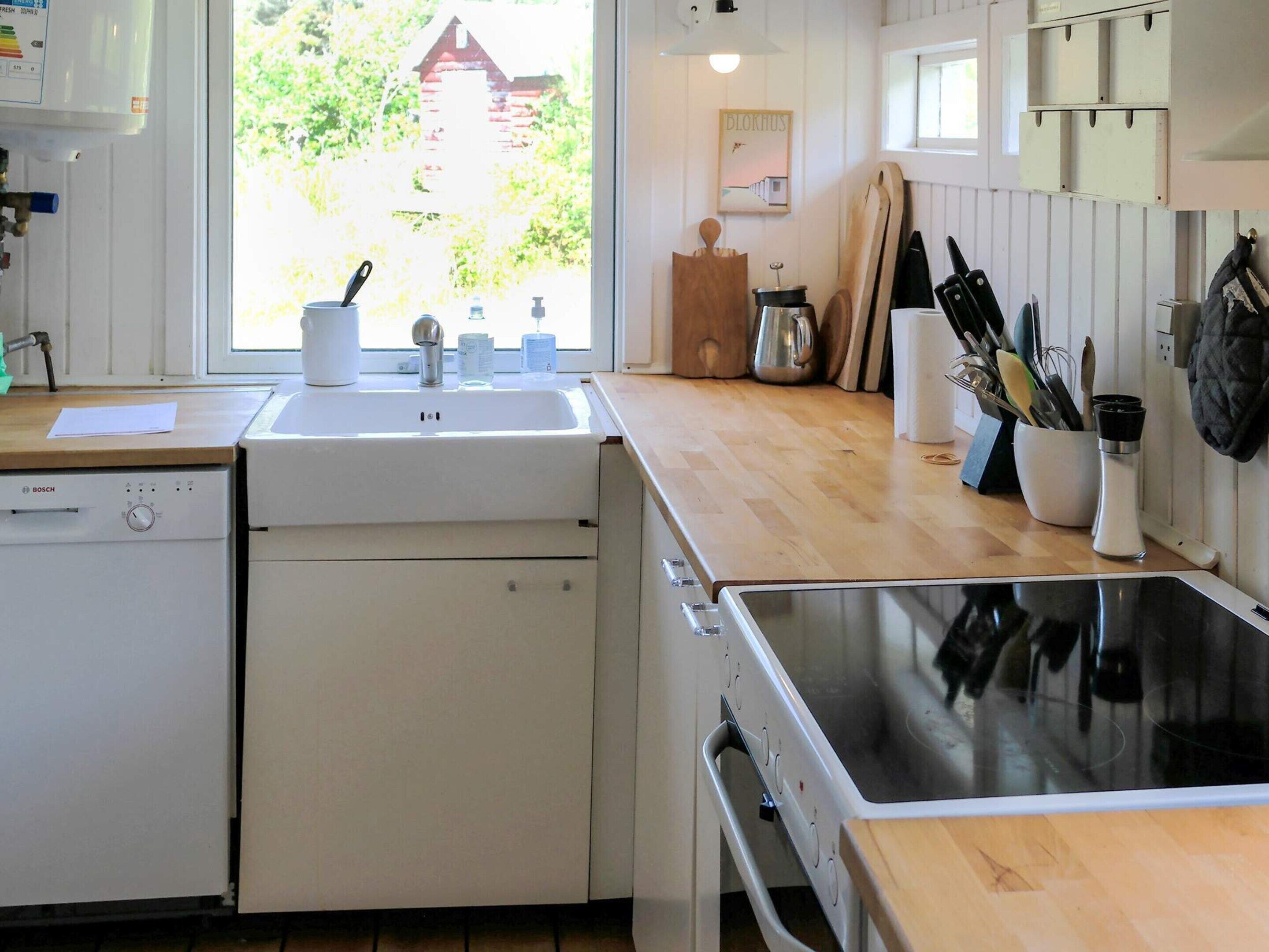 Une cuisine équipée d’un lave-vaisselle Bosch, d’un évier, d’une cuisinière et de plans de travail en bois.