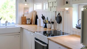 A modern kitchen with white cabinetry, a built-in oven, and a stovetop. - 6 Person Holiday Home in Blokhus (Blokhus)