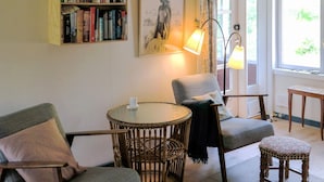 A cozy room with a round table, two armchairs, a small stool, a bookshelf, and a lamp. - 6 Person Holiday Home in Blokhus (Blokhus)