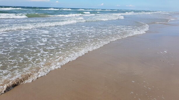 A beach with waves gently lapping onto the shore. - 6 Person Holiday Home in Blokhus (Blokhus)