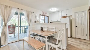 A compact kitchen with white cabinetry, a wooden dining table, and a bench.