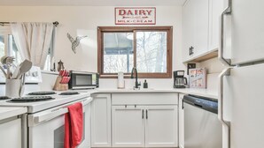 A modern kitchen with white cabinets, a stove, a microwave, and a refrigerator.