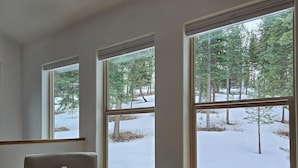 A room with a large window, a chair, and a small table.