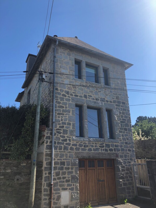 Un edificio de piedra de dos pisos con una puerta y ventanas de madera.