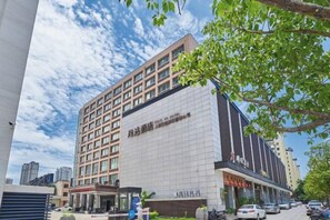 A multi-story hotel with a modern facade, a visible entrance, and a parking area. - Fengda Hotel (Putian)