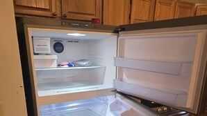 A kitchen with a built-in refrigerator, wooden cabinets, and a tiled floor.