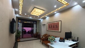 A reception area with a desk, chairs, a potted plant, and a framed artwork on the wall. - Qufu Ancient City Hotel (Sankong Scenic Area) (Qufu)