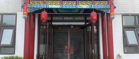 Un edificio tradicional con una entrada decorativa y plantas en macetas.