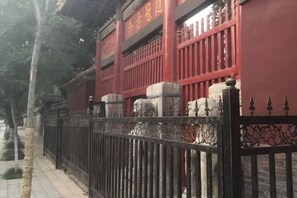 A traditional building with a red facade, a black metal fence, and stone pillars. - Qufu Ancient City Hotel (Sankong Scenic Area) (Qufu)