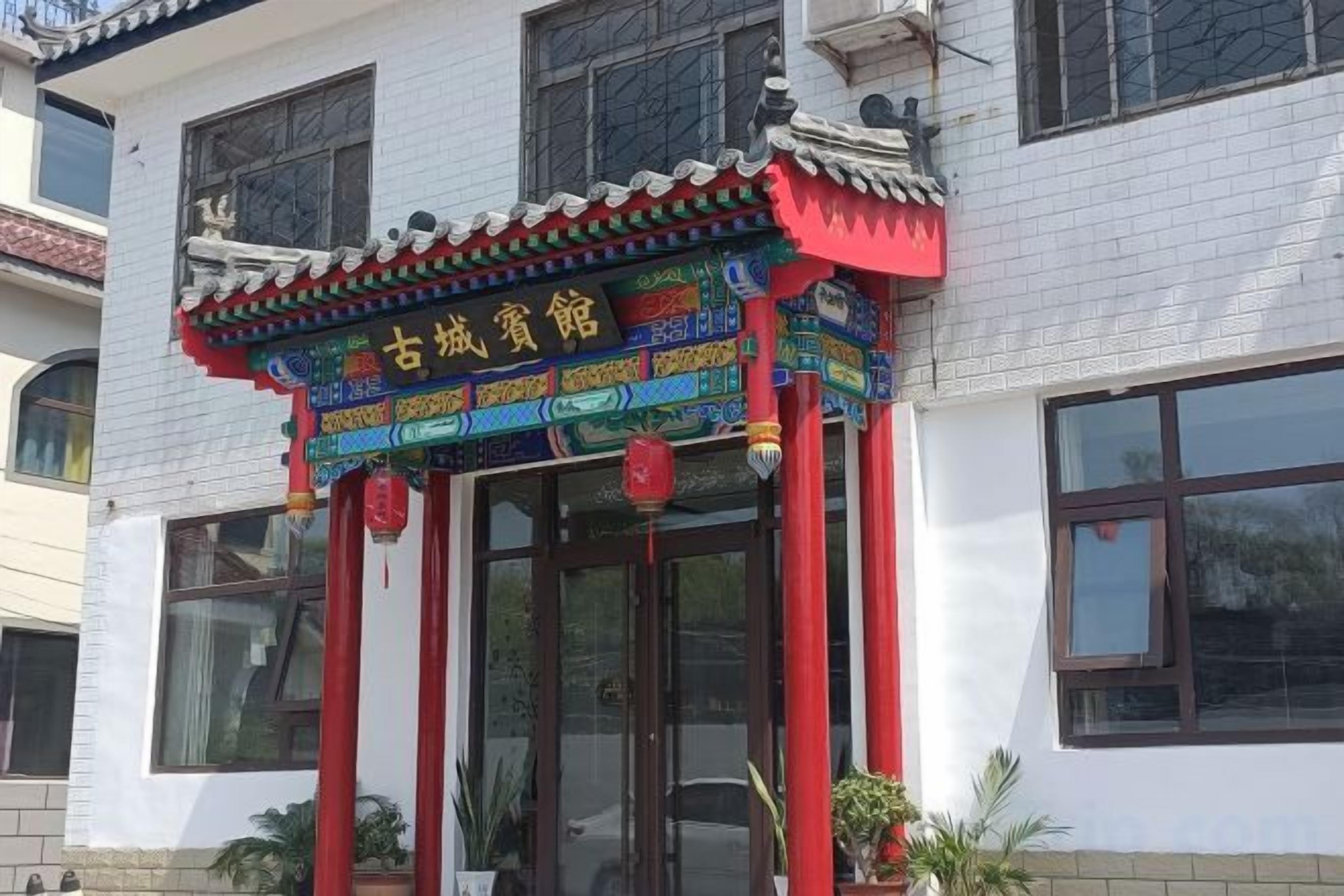 A traditional building with a decorative entrance featuring a colorful roof and red pillars.