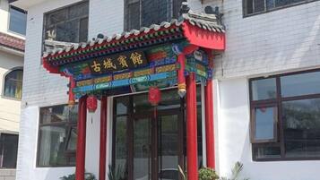 A traditional building with a decorative entrance featuring a colorful roof and red pillars.