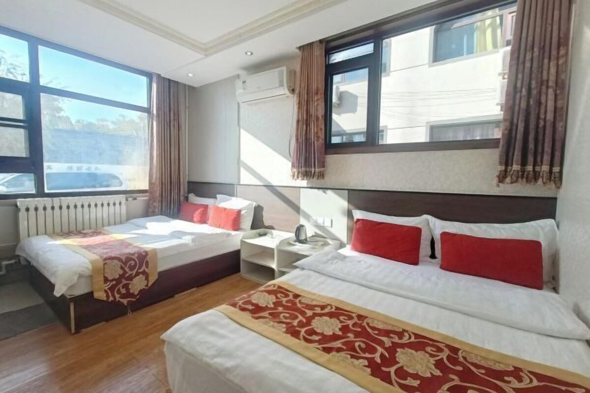Una habitació d'hotel amb dos llits, una finestra, un radiador i una taula.