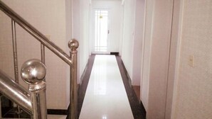 A hallway with a shiny metal staircase on the left, leading to a door at the end. - Qufu Ancient City Hotel (Sankong Scenic Area) (Qufu)