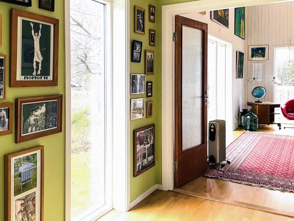 Une pièce avec un plancher en bois, un tapis rouge et une porte qui donne sur une autre pièce.