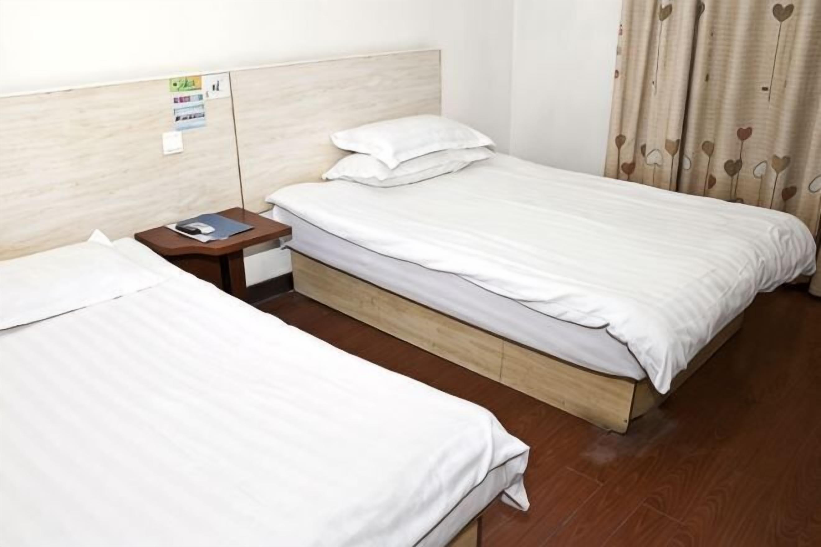 Two single beds with wooden frames, a nightstand with a lamp, and a wall-mounted sign.