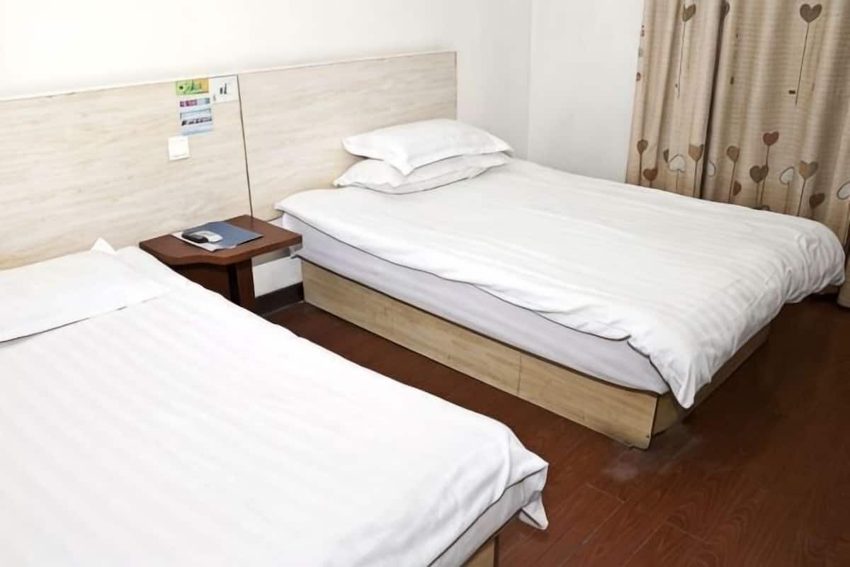 Two single beds with wooden frames, a nightstand with a lamp, and a wall-mounted sign.