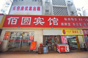 A storefront with a red sign, glass doors, and a small display area outside.