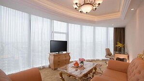 A modern living room with a television, a glass coffee table, and two sofas. - Vienna Hotel (Guangzhou)