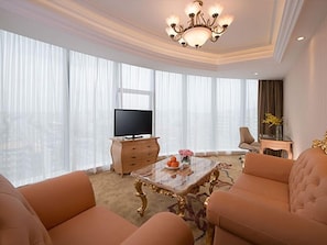 A modern living room with a television, a glass coffee table, and two sofas.