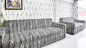 Una habitació amb un sofà estampat de cebra, un quadre abstracte emmarcat i un fons de pantalla amb dibuixos.