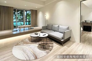 A modern living room with a grey sofa, a round coffee table, and a bench by the window.