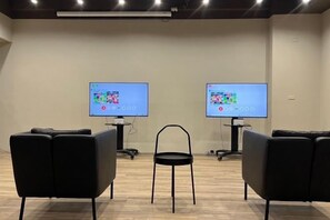 A room with two screens, a chair, and black seating. - Crownshine Resort (Yilan)