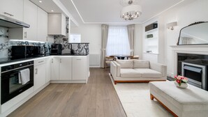 A modern kitchen with white cabinets, a black microwave, and a marble backsplash.