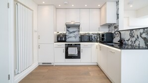 A modern kitchen with white cabinetry, a marble backsplash, and a built-in oven.