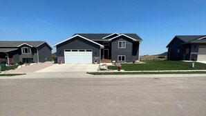 A residential area with modern houses, a clear sky, and a large open driveway. - Sturgis Rally Rental! (Sturgis)