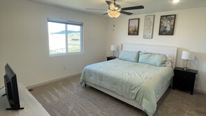 A bedroom with a bed, ceiling fan, window, and a desk with a TV. - Sturgis Rally Rental! (Sturgis)