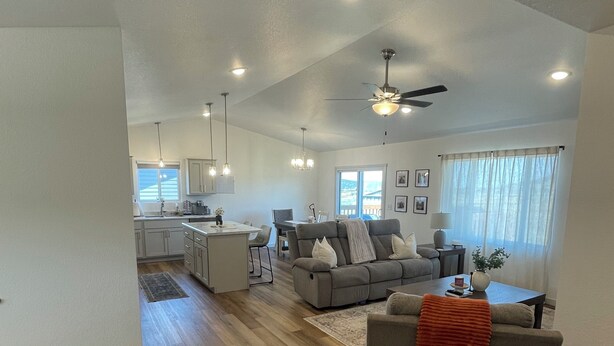 A spacious living area with a kitchen, dining area, and a large window with curtains. - Sturgis Rally Rental! (Sturgis)