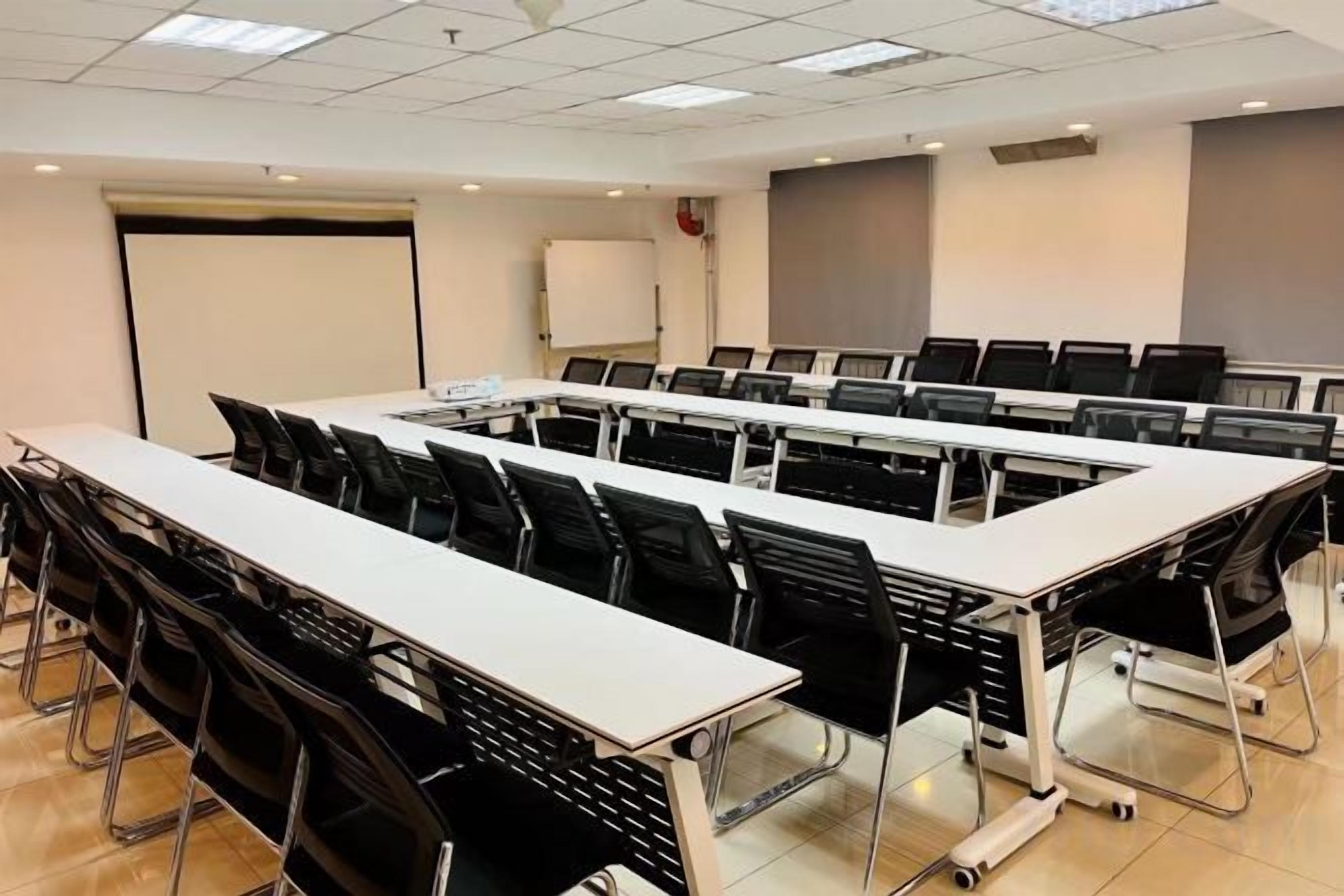 A conference room with a long table, black chairs, and a whiteboard.