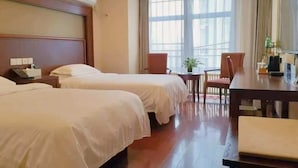 A hotel room with two beds, a wooden headboard, a large window with curtains, a small table with a chair, and a TV. - GreenTree Inn (Beijing Olympic Park National Tennis Center Hotel) (Beijing)