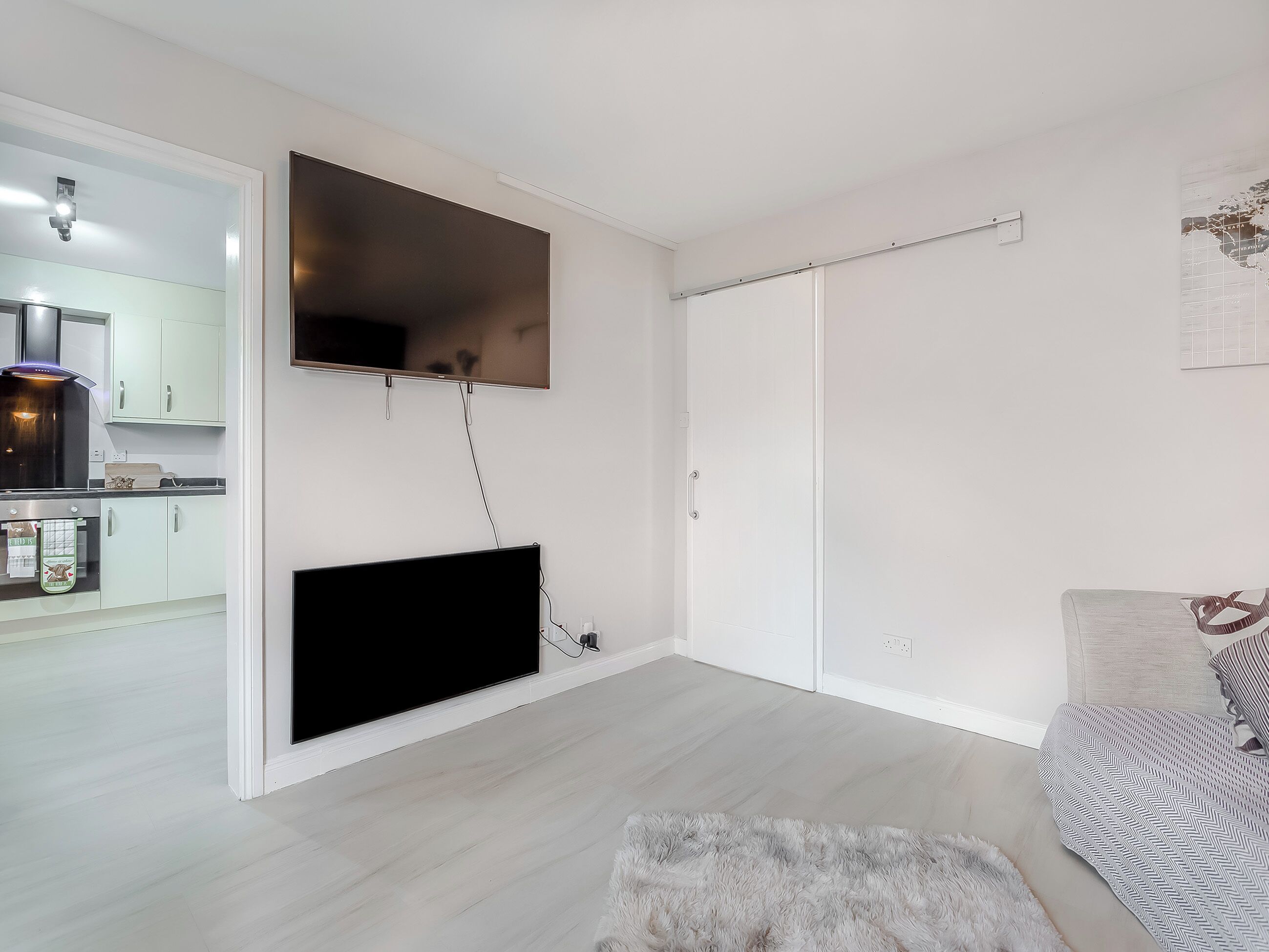 A modern living room with a flat-screen TV mounted on the wall, a sofa, and a fluffy rug.