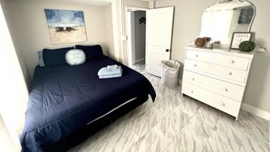 Une chambre à coucher comprenant un lit, une commode, un miroir et une porte donnant sur une autre pièce.