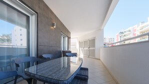 Ein Balkon mit Glastisch und Stühlen, Blick auf Gebäude und ein gefliester Boden.
