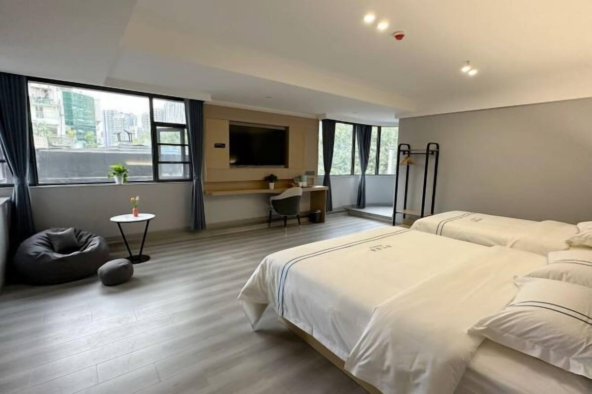 Una habitació d'hotel moderna amb un llit gran, una taula de treball, una cadira, una taula petita i vista a la ciutat a través de la finestra.